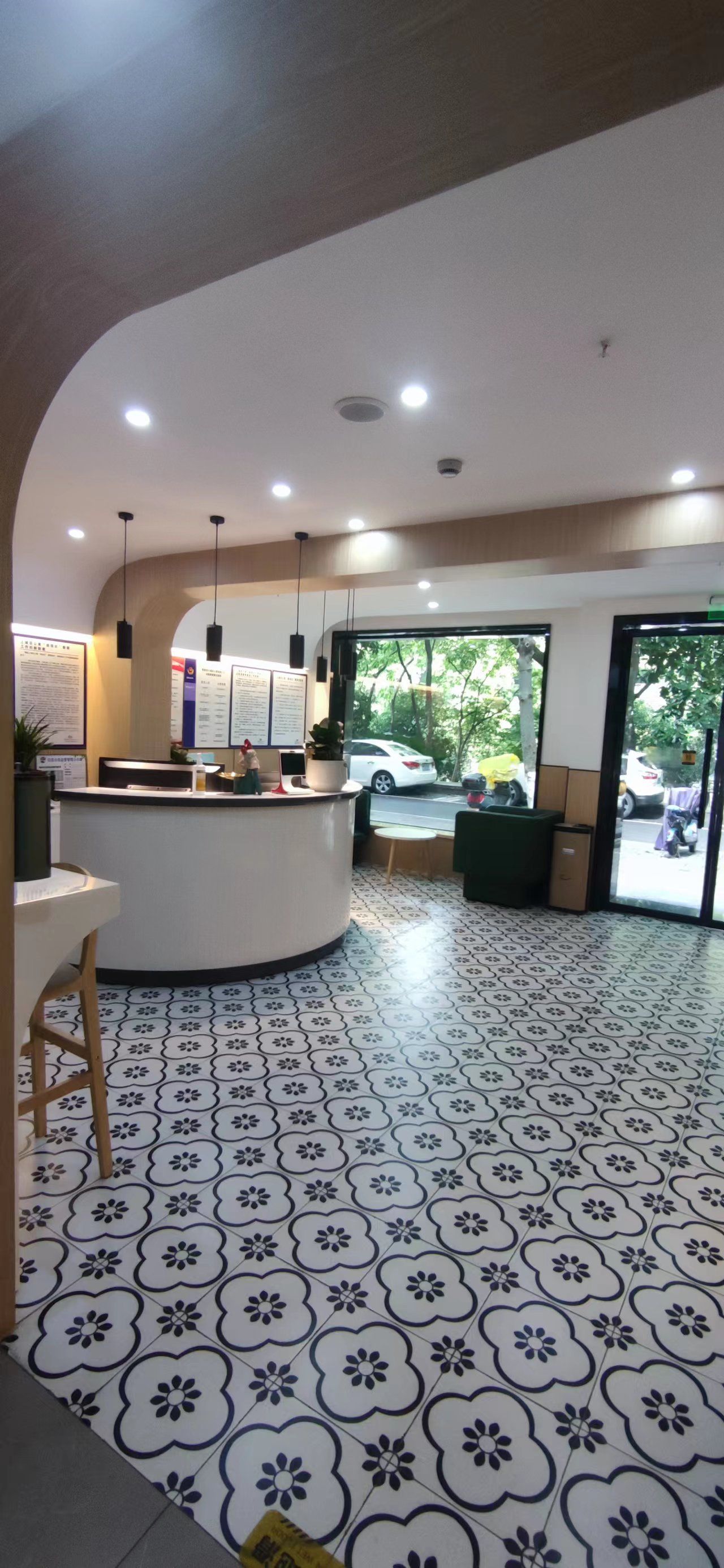 A reception area with a curved counter, hanging lights, and a view of the street outside.