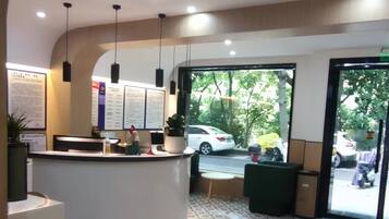 A reception area with a curved counter, hanging lights, and a view of the street outside.