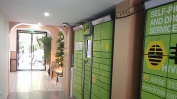 A hallway with green lockers, a sign for self-service and drop-off, and a door leading outside.
