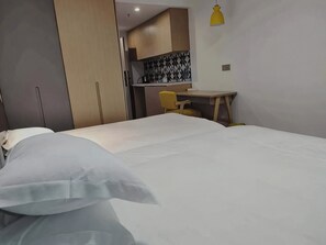 Habitació d'hotel amb un llit, escriptori i petita cuina.