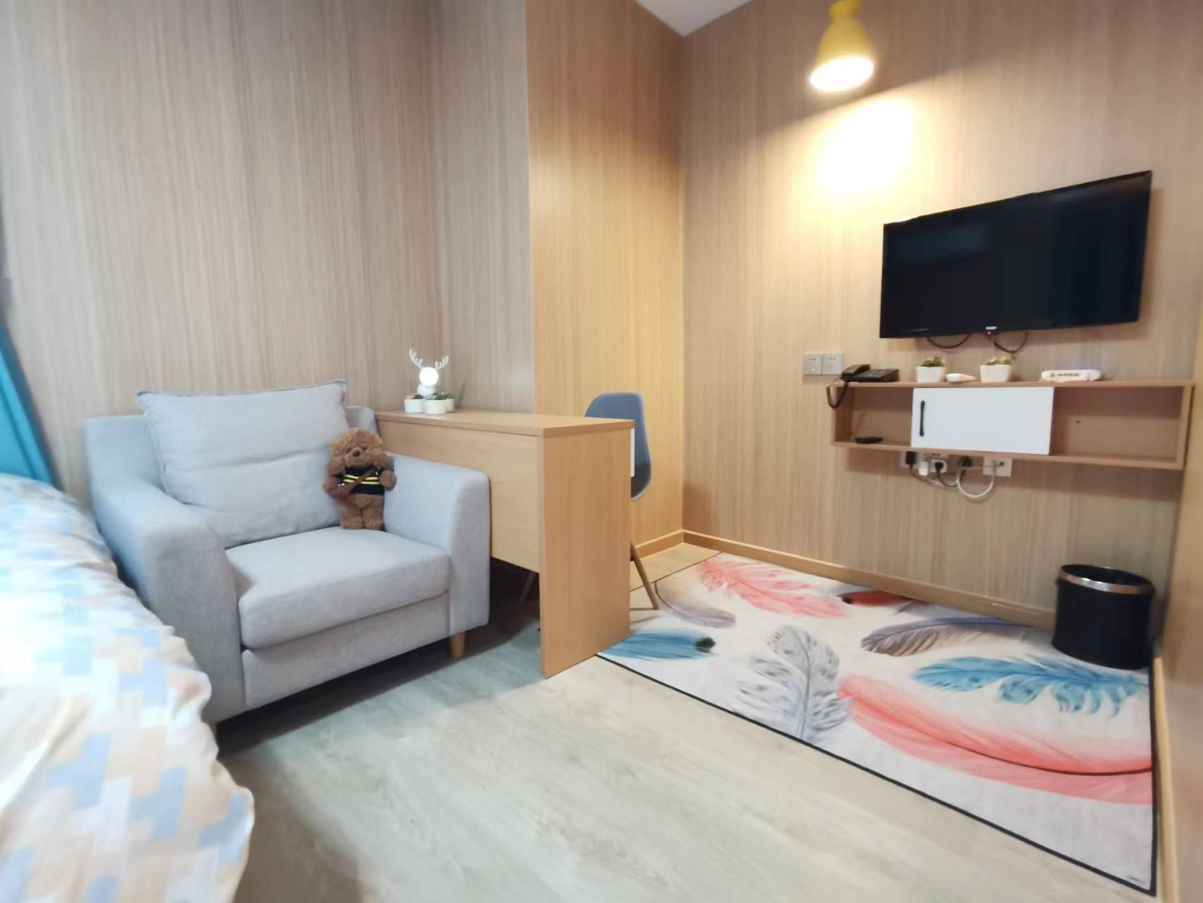 A hotel room with a sofa, a desk, a television, and a small decorative item.