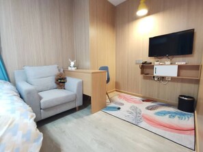 Habitació d'hotel amb un sofà, un escriptori, una televisió i un objecte decoratiu petit.