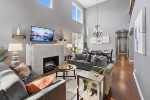 Ein modernes Wohnzimmer mit Kamin, Fernseher und Essbereich.