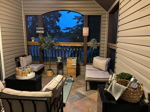 Eine überdachte Veranda mit Gartenmöbeln, einem kleinen Tisch und einem Blumentopf.
