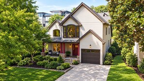 Ein zweistöckiges Haus mit Veranda, Garage und gepflegtem Rasen.
