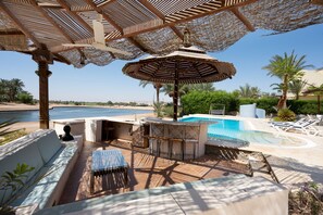 A poolside area with a bar, seating, and a view of the sea. - Vesta - Luxury Villa - 4BR - North Golf II (El Gouna)