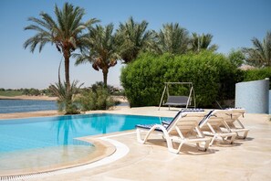 A swimming pool with lounge chairs and a view of the sea. - Vesta - Luxury Villa - 4BR - North Golf II (El Gouna)