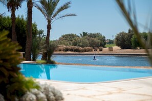 A swimming pool with a clear view of the water, surrounded by palm trees and a distant landscape. - Vesta - Luxury Villa - 4BR - North Golf II (El Gouna)