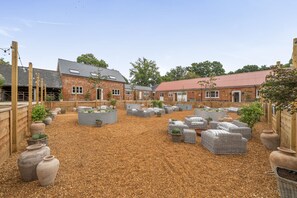 Een binnentuin met bakstenen gebouwen, terrasmeubels en plantenbakken.