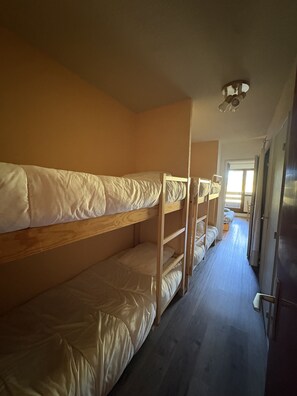 A room with bunk beds, a ceiling fan, and a door leading to another room. - Cabin studio with mountain view (Orcières)