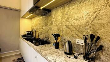 A modern kitchen with granite countertops, stainless steel appliances, and a black range hood.