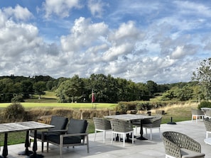 An outdoor patio with tables and chairs, overlooking a golf course. - Willow Brook, Hamptworth, Hampshire (Salisbury)