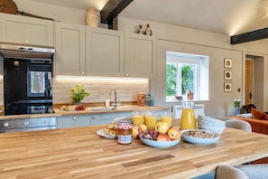 A modern kitchen with a wooden countertop, a built-in oven, and a window providing natural light. - Willow Brook, Hamptworth, Hampshire (Salisbury)
