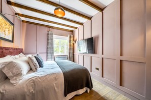 Ein Schlafzimmer mit einem Bett, einem Fernseher und einem Fenster mit Vorhängen.