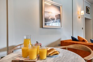 Ein Frühstückstisch mit Orangensaftgläsern, einer Auswahl an Gebäck und einem gerahmten Bild an der Wand.