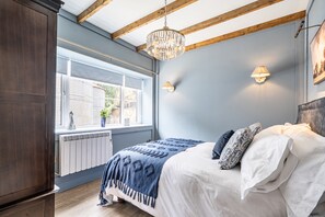 A bedroom with a bed, a window, a radiator, and a chandelier. - Fern Cottage, Hamptworth, Hampshire (Salisbury)
