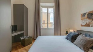 A bedroom with a bed, a television, a window with curtains, and a painting on the wall. - MODERN 3-BEDROOM FLORENCE HOME NEAR DUOMO & PIAZZA DELLA REPUBBLICA (Firenze)
