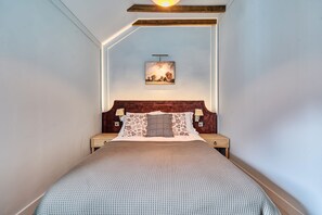 Ein Schlafzimmer mit einem Bett, einem Nachttisch, einer Lampe und einem Bild an der Wand.