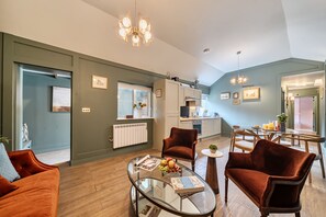 Ein modernes Wohnzimmer mit einem Glastisch, roten Samtstühlen, einer Küchenzeile mit weißen Schränken und einem Essbereich mit einem Glastisch.