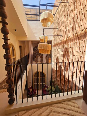 A modern interior with a staircase, a hanging light fixture, and a textured wall. - Riad Victoria (Marrakech)