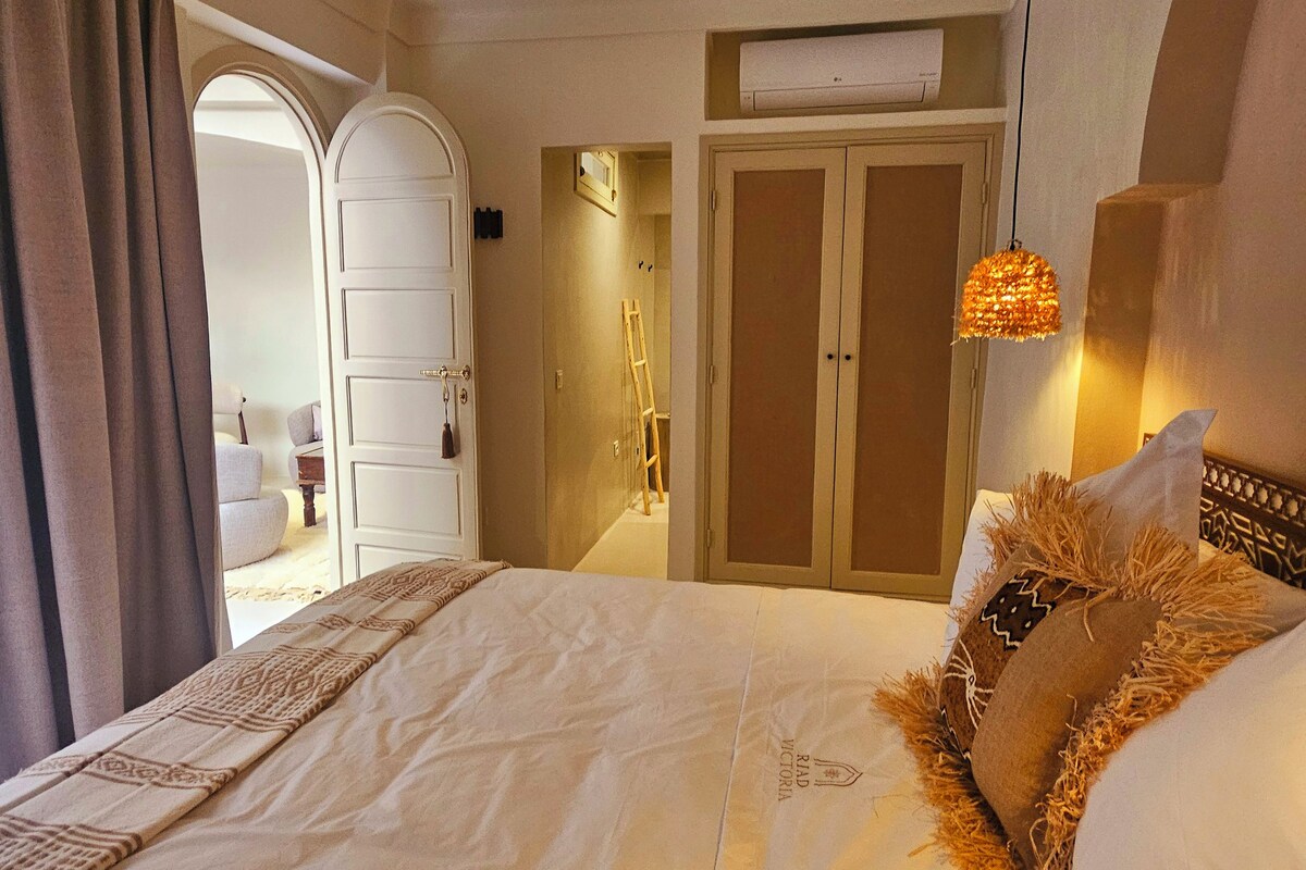 Habitació d'hotel amb un llit, un ventilador de sostre, un armari i una lluminària penjant.