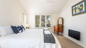 A bedroom with a bed, a dresser, a mirror, a window with blinds, and a framed picture on the wall.