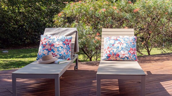 Two lounge chairs with floral-patterned cushions on a wooden deck.
