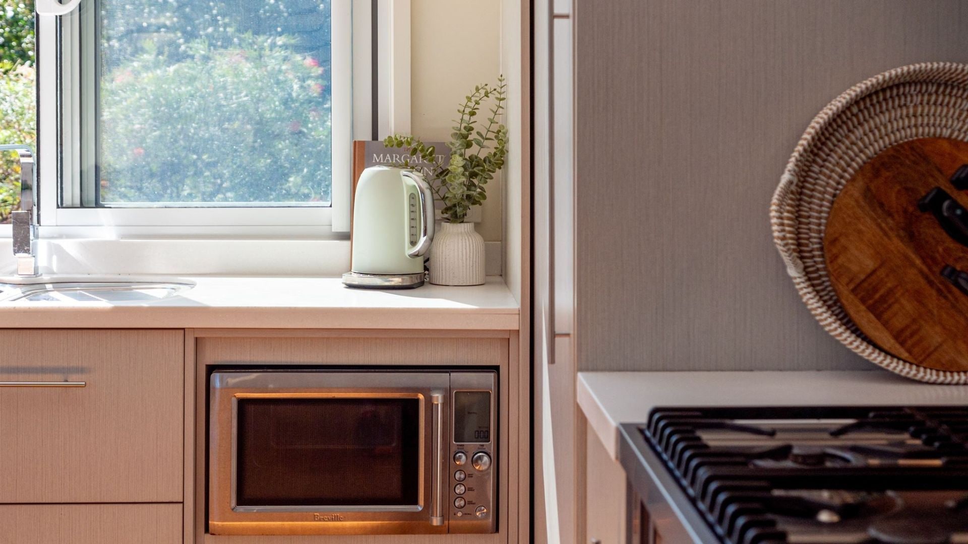 Una cocina equipada con microondas, hervidor y estufa.