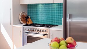 A kitchen with a gas stove, oven, and a teal backsplash.
