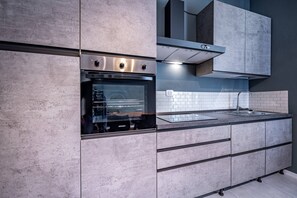 Eine moderne Küche mit Einbauofen, Edelstahl-Dunstabzugshaube und einer großen Arbeitsplatte mit Spüle.