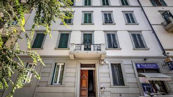 A building with multiple windows, a wooden door, and a balcony.