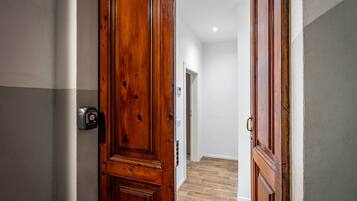 Un couloir avec des portes en bois, un interrupteur et un thermostat fixés au mur.