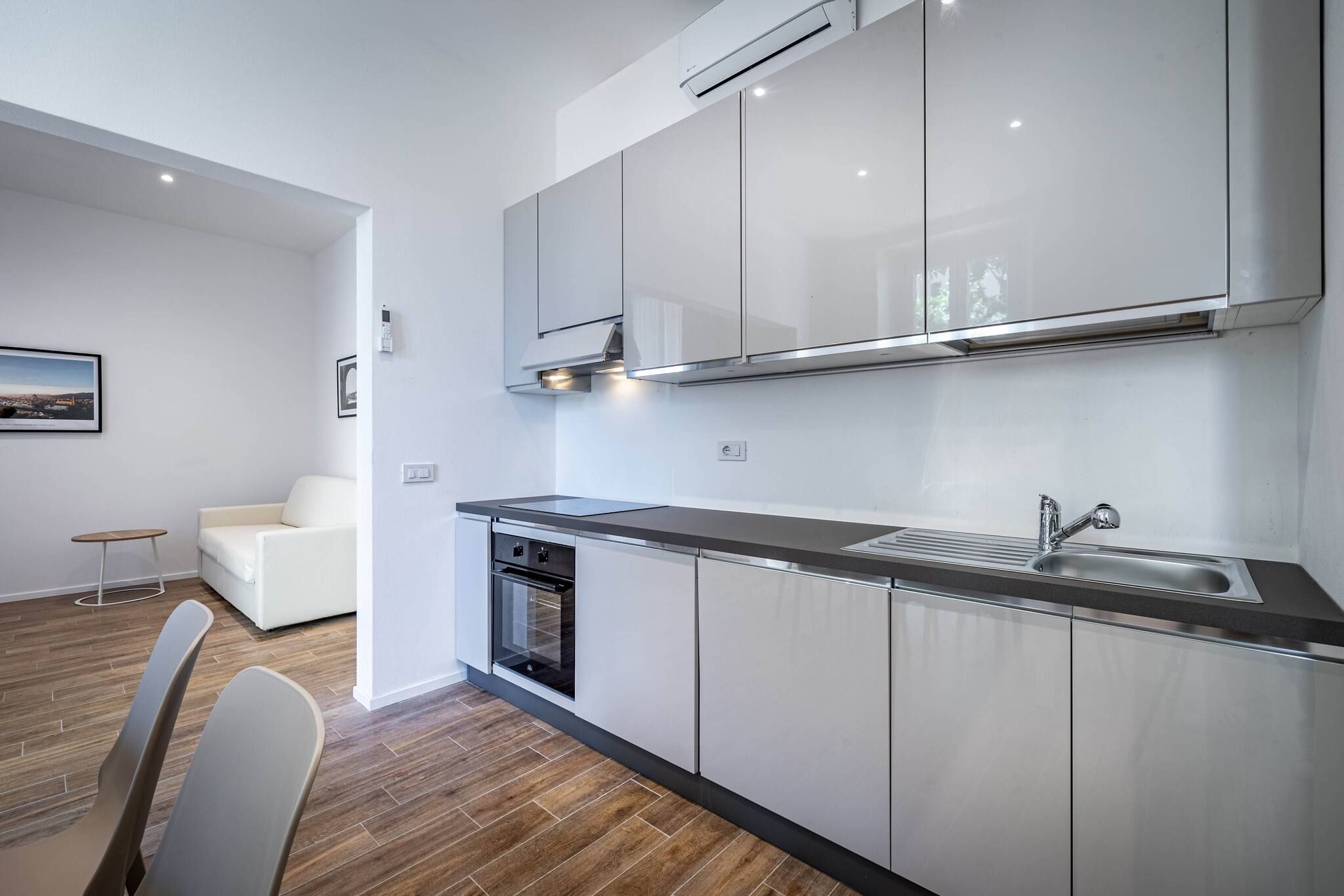 A modern kitchen with stainless steel appliances, a built-in oven, and a large window above the sink.