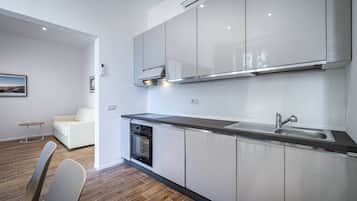 A modern kitchen with stainless steel appliances, a built-in oven, and a large window above the sink.