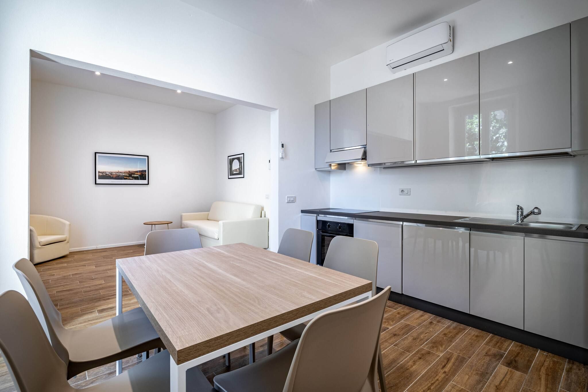 Una cocina moderna con armarios blancos, una mesa de comedor de madera y un horno empotrado.