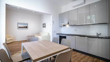 Una cocina moderna con armarios blancos, una mesa de comedor de madera y un horno empotrado.