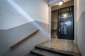 En trappe med et trægelænder, der fører op til en mørk dør med glasruder.