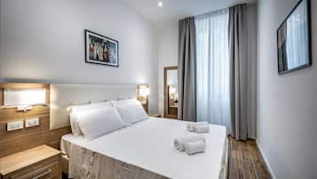 Une chambre d’hôtel avec un grand lit, des lampes de chevet, une table de chevet, une tête de lit en bois, un tableau encadré au mur et une fenêtre avec des rideaux.