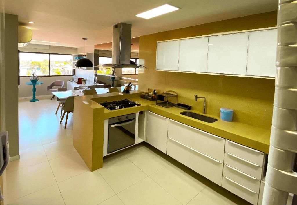Cocina moderna con una isla central, armarios blancos y encimera amarilla.