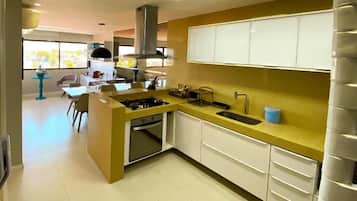 Cocina moderna con una isla central, armarios blancos y encimera amarilla.