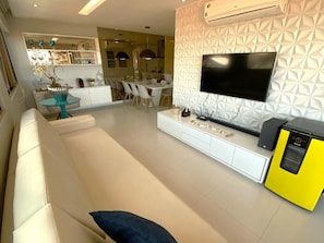 Una sala de estar moderna con un sofá, un televisor y un electrodoméstico amarillo.