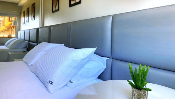 A hotel room with a large bed, a headboard, and a small potted plant on the nightstand. - Cobertura Vista Mar Barra Bali (Barra de São Miguel)