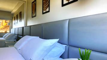 A hotel room with a large bed, a headboard, and a small potted plant on the nightstand.