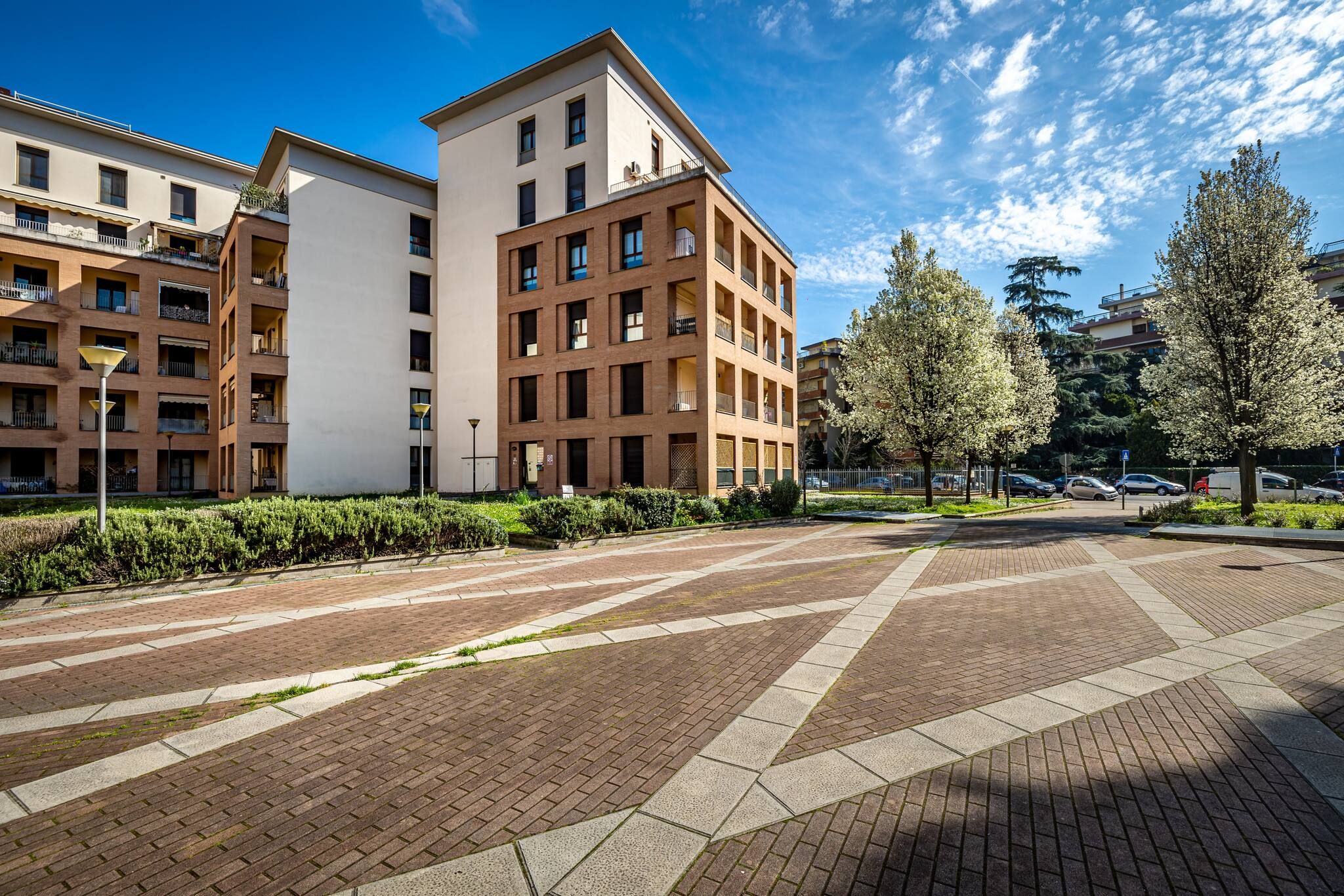 Un moderno edificio residencial con varios balcones y un patio empedrado.