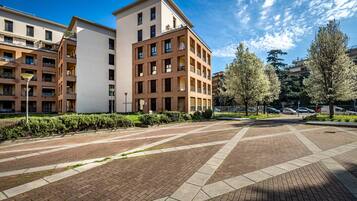Un moderno edificio residencial con varios balcones y un patio empedrado.