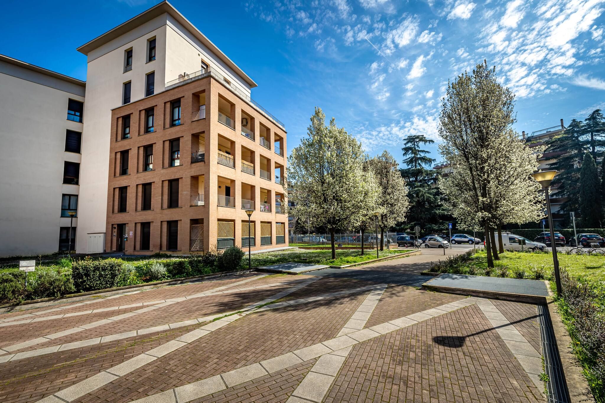 A multi-story residential building with a brick facade, a flat roof, and a balcony on the upper floors.