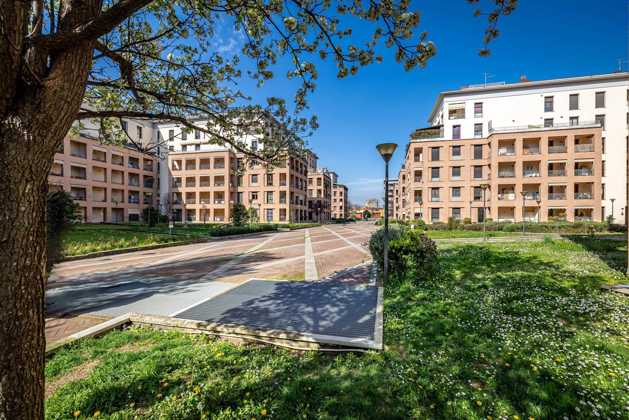 A residential area with multi-story buildings, a paved road, and a grassy area with trees.