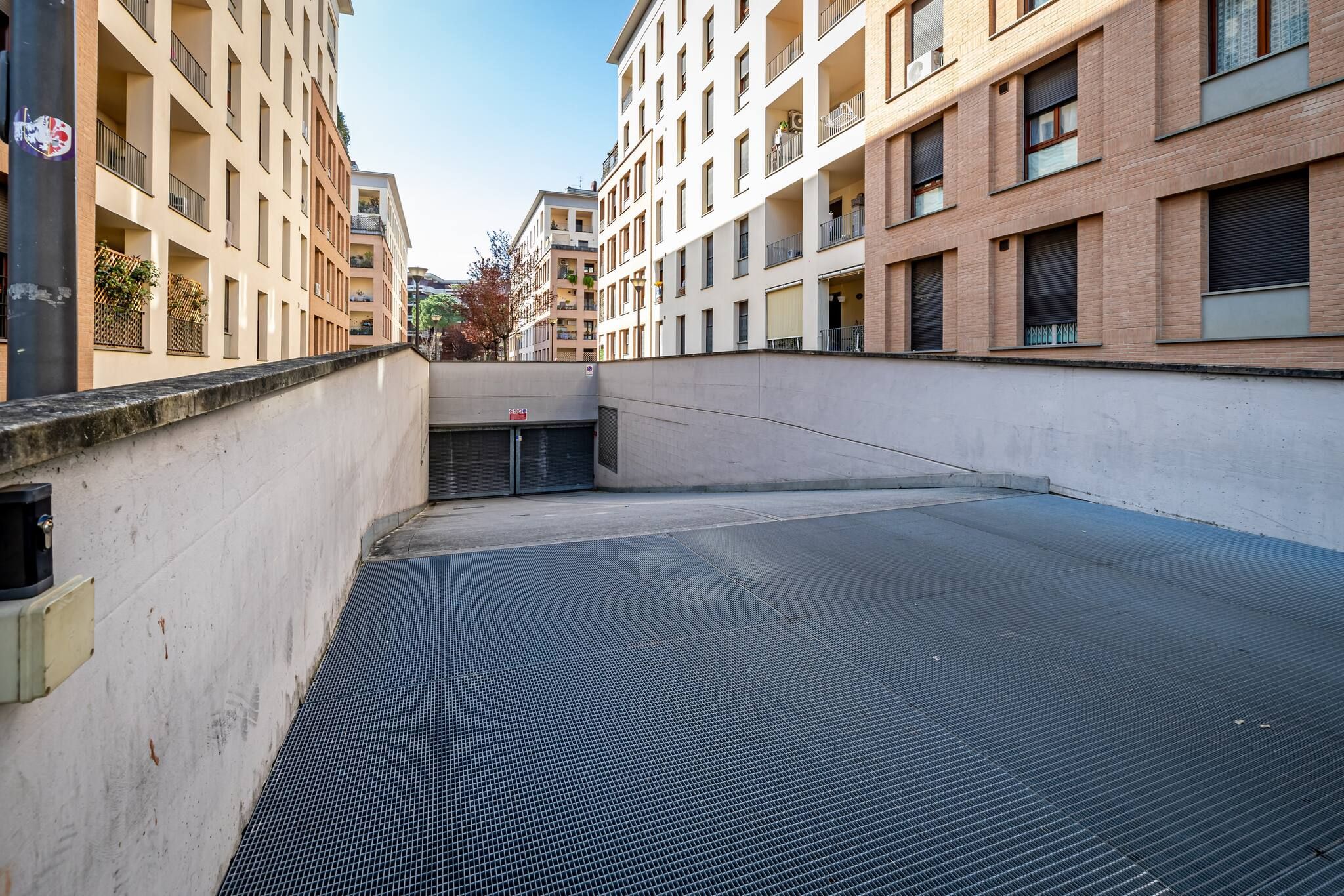 A multi-story residential building with balconies, a gated entrance, and a flat roof.