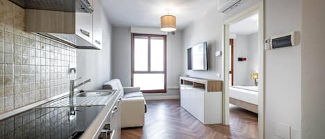A modern kitchen with a herringbone wood floor, a built-in oven, and a large window.
