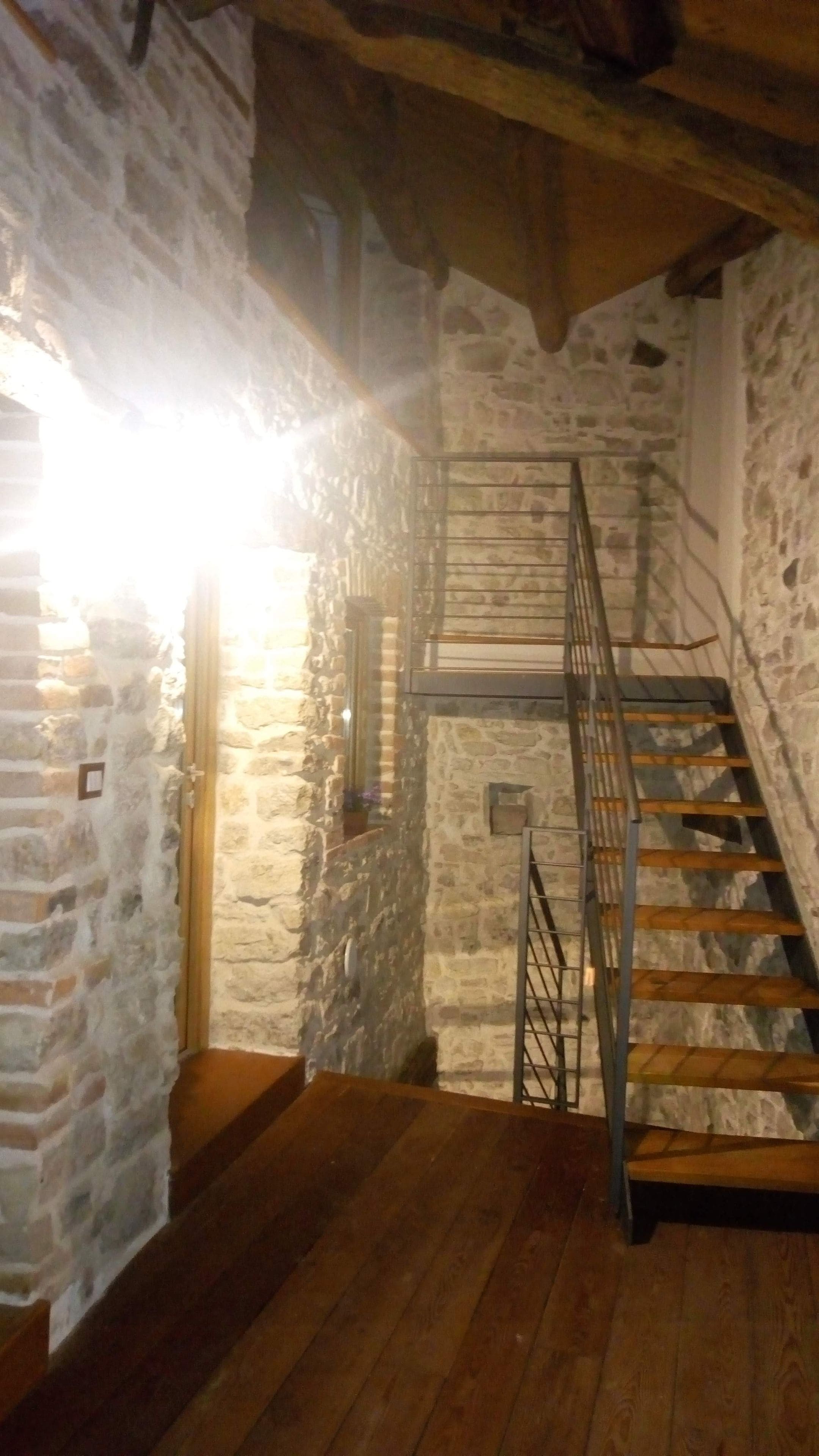 Eine Treppe mit Holzwurf und Metallspindeln, die zu einer Steinmauer führt.
